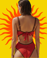 Back view of a red one-piece swimsuit with brown trim against a yellow background